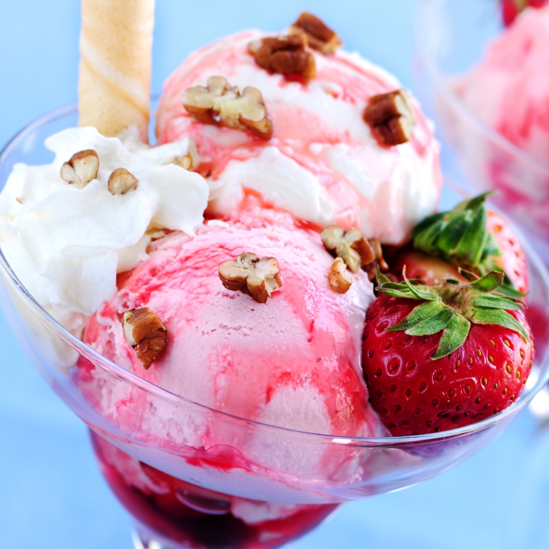 Ice cream sundae in a bowl with a straw and strawberry.